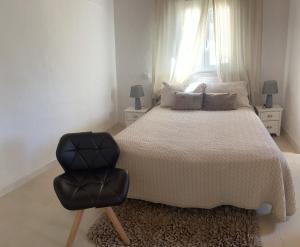 um quarto com uma cama e uma cadeira preta em Apartamento “El Vicho” en la Axarquía em Almáchar