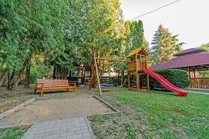 a park with a playground with a slide and a bench at Körösvölgyi Apartmanházak 