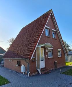 una pequeña casa de ladrillo rojo con puerta blanca en Meerhaus Hieve en Emden