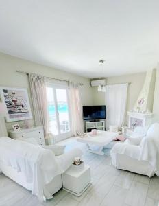 a living room with white furniture and a large window at Fairy home Porto Heli in Porto Heli