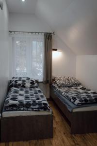 two beds sitting in a room with a window at Domek przy Parku z basenem Rabka in Rabka-Zdrój
