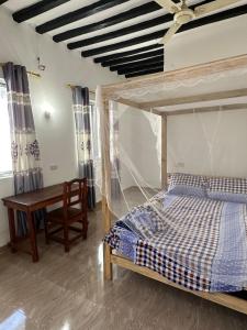 a bedroom with a bed and a table and a desk at Kijiji House Paje in Paje