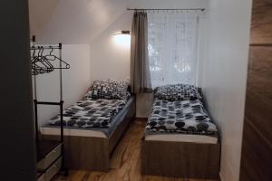 two beds in a room with a window at Domek przy Parku z basenem Rabka in Rabka-Zdrój