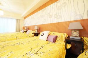 大阪市にあるMATATABI STAY Daikokuchoのホテルルーム 黄色いシーツ付きのベッド2台付