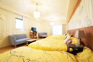 a bedroom with two beds and a couch and a chair at MATATABI STAY Daikokucho in Osaka