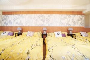 a bedroom with two beds with yellow sheets and two lamps at MATATABI STAY Daikokucho in Osaka