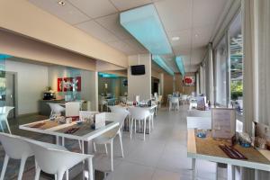 a restaurant with white tables and white chairs at Mercure Brive in Ussac