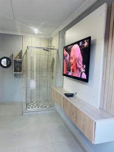 a bathroom with a tv on a wall with a shower at Executive Galaxy Guest House Nkowankowa Extension 2 in Tzaneen
