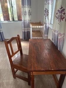 a wooden table and chair in a room with curtains at Kijiji House Paje in Paje