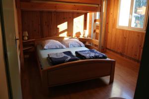 Cama en habitación de madera con 2 almohadas en Les Morillons, en Foncine-le-Bas