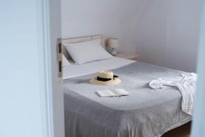 a bed with a hat and a book on it at White Wave Villa, 3min walk from beach in Kamari