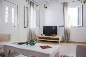 a living room with a tv and a white table at White Wave Villa, 3min walk from beach in Kamari