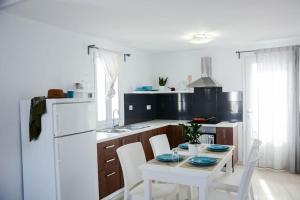 a kitchen with a table and chairs and a white refrigerator at White Wave Villa, 3min walk from beach in Kamari