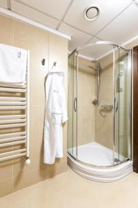 a bathroom with a shower and a white robe at Hotel Crocus in Zakopane