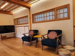 a living room with two chairs and a flat screen tv at IRIRU Luxury Hanok Stay - Eunpyung Hanok village in Seoul