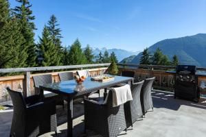 une table et des chaises sur un balcon avec un poêle dans l'établissement Chalet Charbray, à La Tzoumaz
