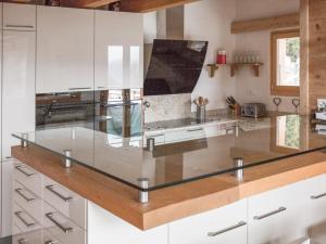 une cuisine avec des armoires blanches et un comptoir en verre dans l'établissement Chalet Charbray, à La Tzoumaz 19 autres photos