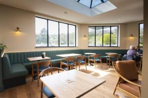 un restaurante con mesas, sillas y ventanas en Penrhos Park, en Llanrhystyd