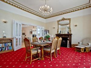Riviera Mansion, Torquay في توركواي: غرفة طعام مع طاولة وكراسي على سجادة حمراء
