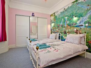 two beds in a room with a painting on the wall at Riviera Mansion, Torquay in Torquay