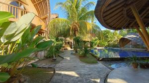 a courtyard with a pool and palm trees and a building at Hawera Village in Kuta Lombok