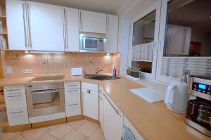 a kitchen with white cabinets and a sink at Ferienwohung DaHeim in Bovenden