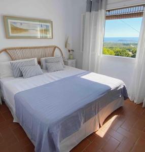 a bedroom with a large bed with a large window at La Terraza de la Sabina in Es Mercadal