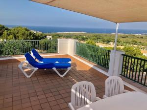 einen Balkon mit blauen Liegestühlen und Meerblick in der Unterkunft La Terraza de la Sabina in Es Mercadal