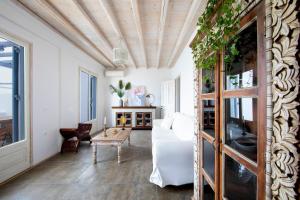 una sala de estar con muebles blancos y techo de madera. en MYKONOS-ORNOS -VILAS ANGEL ALICE DEMI -POOL HOLIDAYS with VIEW, en Mykonos ciudad