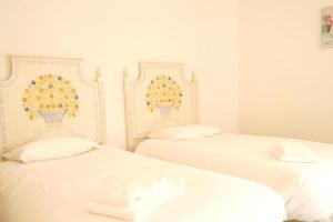 two white beds in a room with flowers on the wall at Villa Francesa Guest House in Lagos