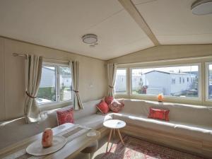 a living room with a white couch and windows at Lighthouse Holiday Retreat in West Mersea