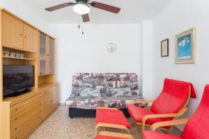 a living room with red chairs and a bed at Edificio Flamingo in Gandía