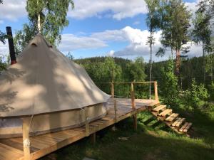a yurt on a wooden platform with a bench at Frisbo Lodge - Glamping tent in a forest, lake view in Bjuråker