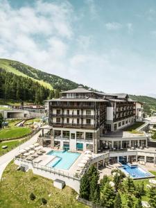 een hotel met een zwembad en een resort bij Falkensteiner Aktiv & Familienhotel Cristallo in Katschberghöhe