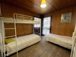 two bunk beds in a room with wooden walls at Elan 19 - Appartement 3 chambres in La Clusaz