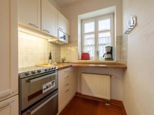 a kitchen with white cabinets and a sink and a window at Feriendorf Rugana - Komfort Appartement mit 2 Schlafzimmern und Terrasse D03 in Dranske +2 photos