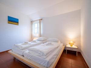 un grand lit blanc dans une chambre avec une fenêtre dans l'établissement Feriendorf Rugana - Budget Appartement mit 2 Schlafzimmern und Terrasse A26, à Dranske 3 autres photos