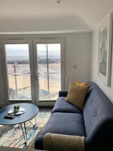 a living room with a blue couch and a table at Modern studio apartment with stunning views! in St Ives