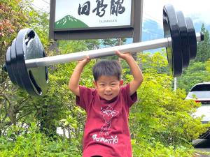 a young boy holding a barbell over his head at 筋肉と自然と遊ぶ宿 田島館 in Takayama