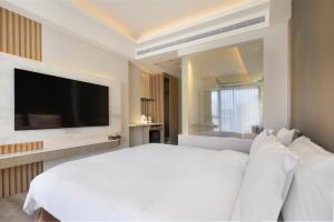 a bedroom with a white bed and a flat screen tv at Gamalan Star Hotel in Jiaoxi