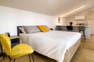 a bedroom with a bed and a yellow chair at Alfea Deluxe Loft & Rooms in Trento