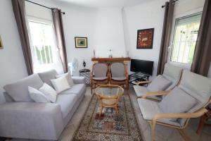 sala de estar con sofá, sillas y TV en Villa Xoriguer, en Denia