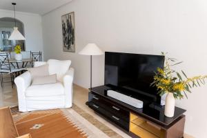 a living room with a television and a white chair at Los Piños, 2 Bedroom Apartment with panoramic view in Benahavís
