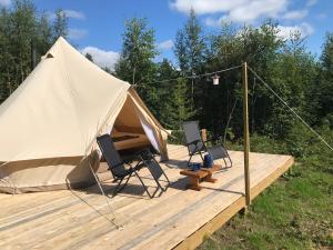 a tent with two chairs and a basketball hoop at Frisbo Lodge - Glamping tent in a forest, lake view in Bjuråker