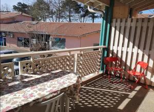 eine Veranda mit einem Bett und zwei roten Stühlen in der Unterkunft Joli duplex ensoleillé in Capbreton