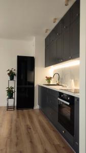 a kitchen with black cabinets and a black refrigerator at Apartament Szmaragdowy Light Tower Aquapark Reda in Reda