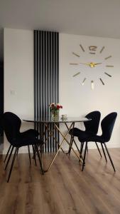 a dining room with a table and chairs and a clock at Apartament Szmaragdowy Light Tower Aquapark Reda in Reda