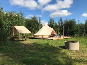 a tent and a picnic table in a field at Frisbo Lodge - Glamping tent in a forest, lake view in Bjuråker