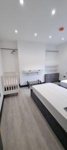 Modern 2BD Flat في لندن: غرفة بيضاء كبيرة مع سرير كبير ومقعد