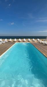 a swimming pool with chairs and the ocean in the background at Apart-Hotel Poseidon in Odesa